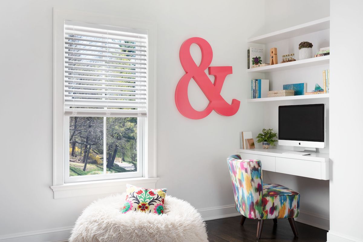 White faux wood blinds in a kid's bedroom, complemented by an ampersand design engraved on the wall.