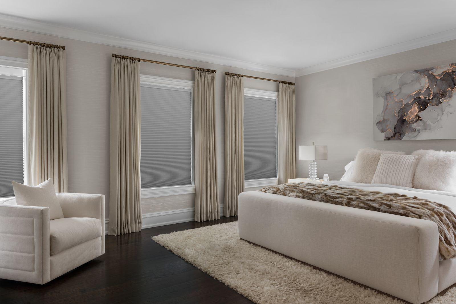 The bedroom has three large windows with drapery and energy-efficient cellular blinds with blackout filters.