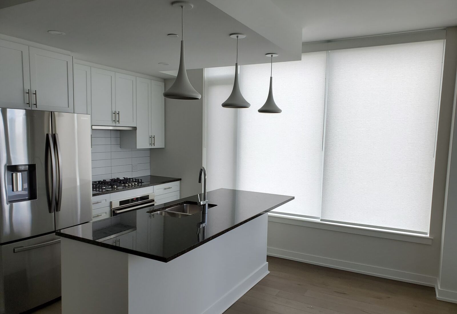 White solar shades with %1 openness cover large kitchen windows, providing complete privacy.