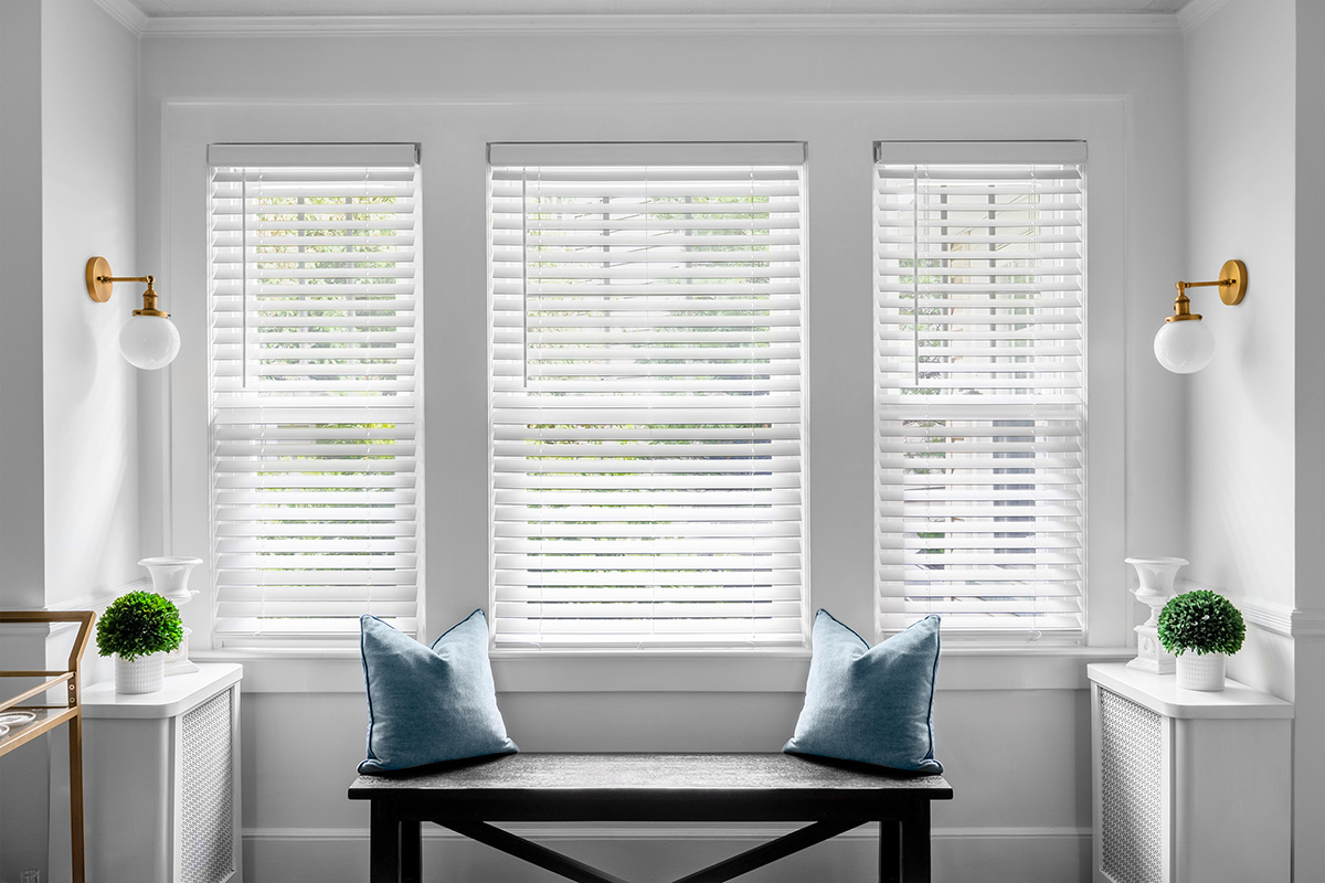 A stunning white living room is beautifully complemented by classic faux wood blinds.