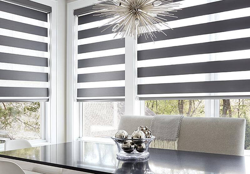 White and grey striped motorized Cascade sheer shades gently cascade down, transforming a dining room modern haven for intimate gatherings.