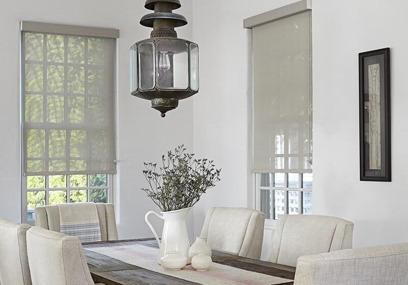 Tan motorized solar shades allow light and views to enter a modern dining room.