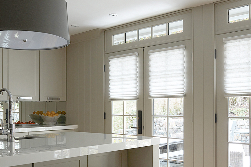 Motorized pleated shades on French doors in a kitchen let light in while covering the windows.