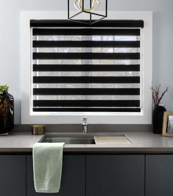 Une grande fenêtre dans une cuisine moderne est habillée de stores transparents Cascade à rayures horizontales sombres.