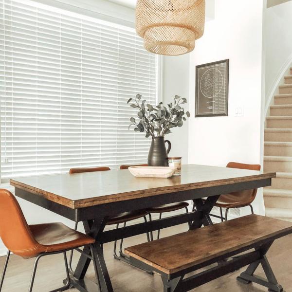 A rustic dining room with white faux wood blinds