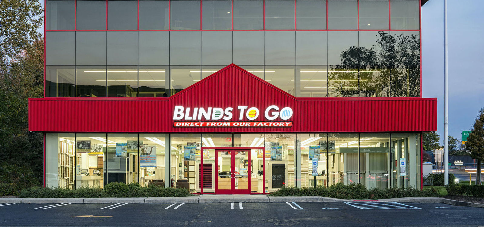 A large Blinds To Go showroom, with its signature red roof,  viewed from the parking lot.