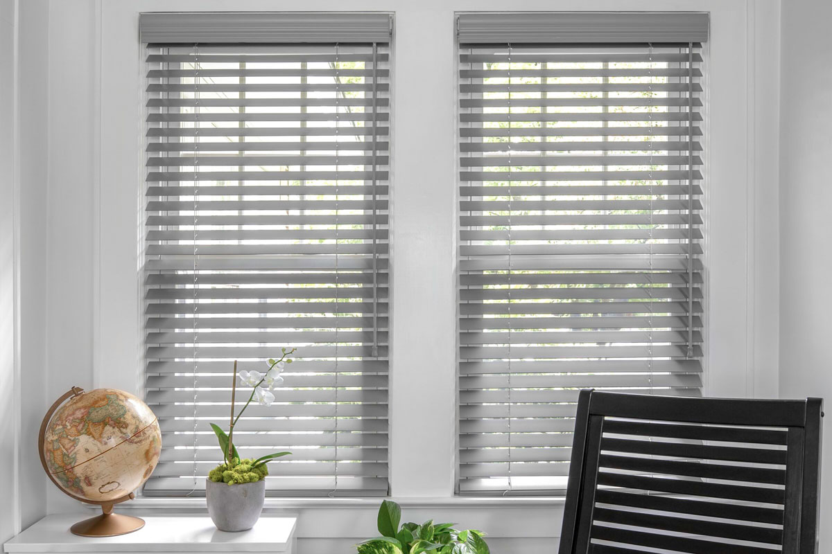 Grey tone natural wood blinds cover two windows in a sitting room