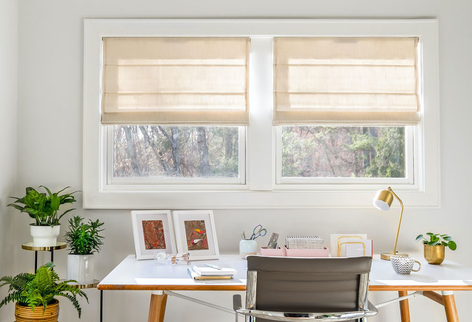 A modern home office features Roman shades on a double window.