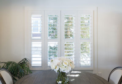 Shutters cover a large window in small dining room.