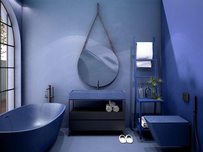 A stunning modern bathroom with blue walls features a blue sink, a blue toilet and a blue free-standing tub.