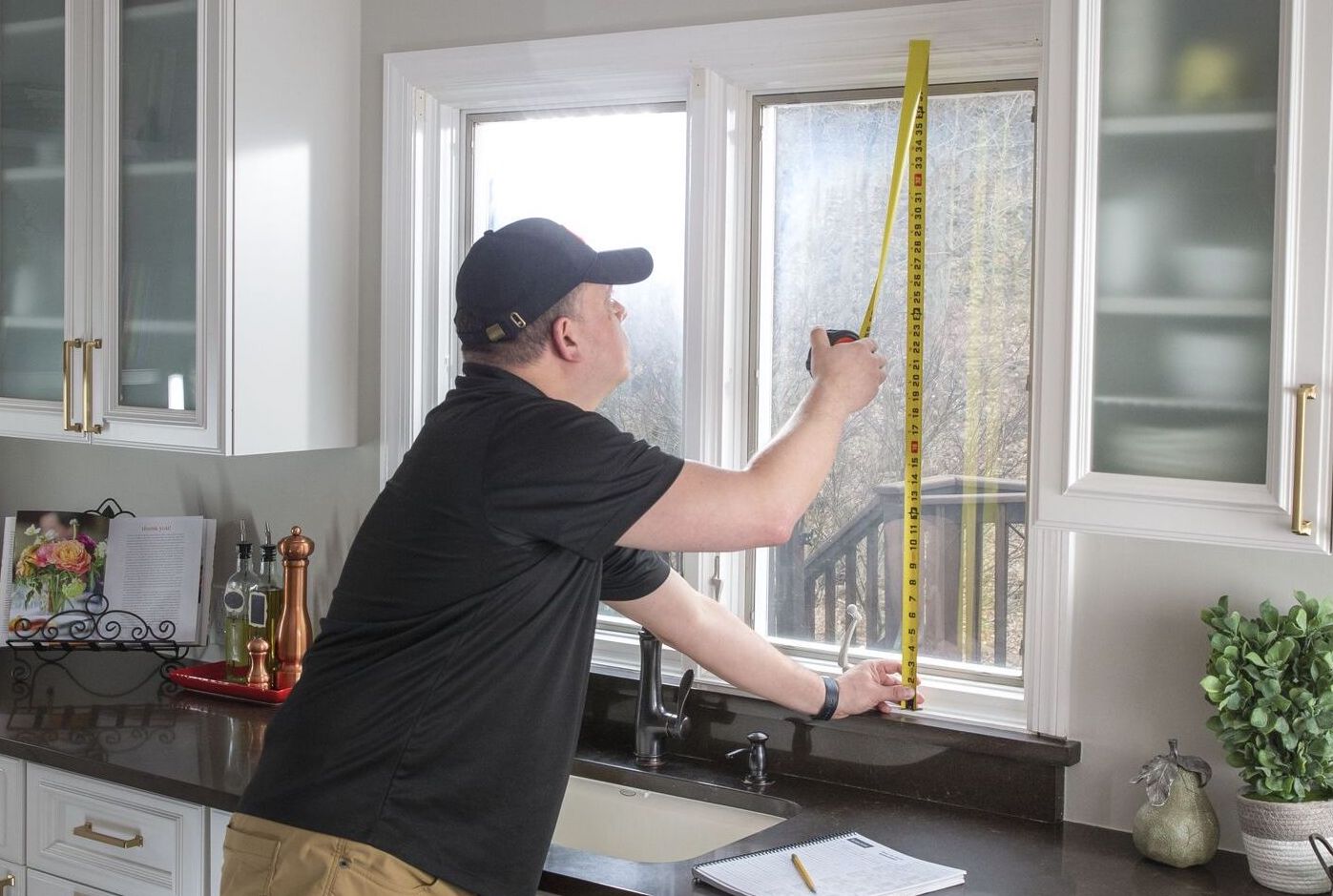 A measure technician measures a kitchen window.