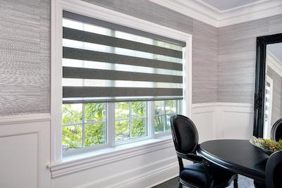 Cascade or zebra striped shades in grey cover a large window in a small dining room.