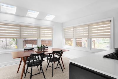A contemporary kitchen features large windows with tan Cascade sheer shades.