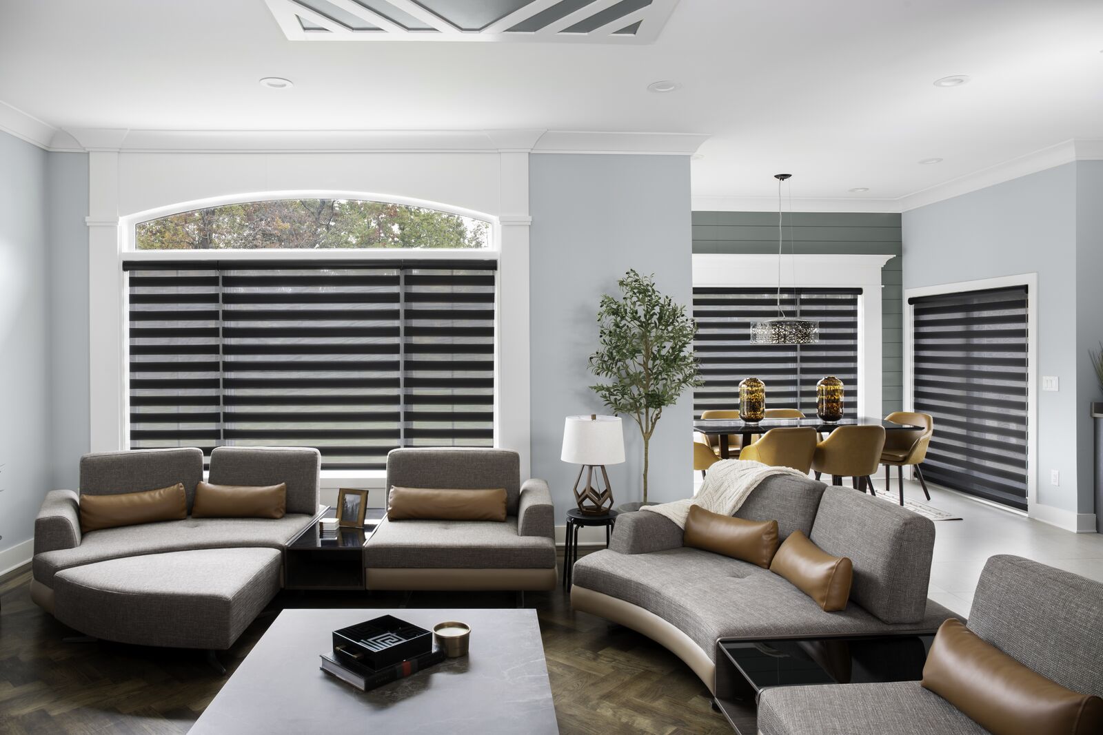 Large windows in a modern living room are covered with Cascade sheer shades with bold dark horizontal stripes