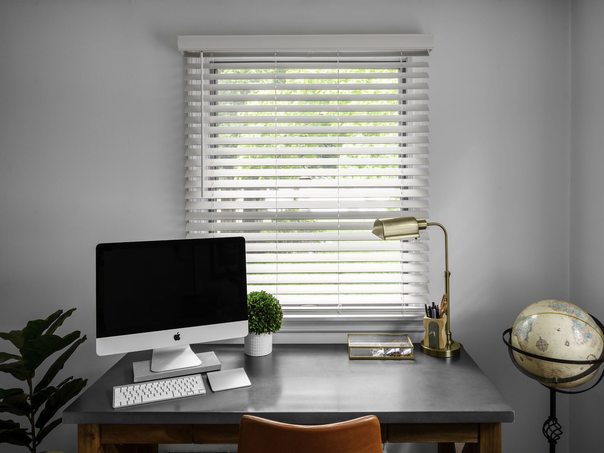 Wood blinds with a valance are outside mounted on a window in a small home office.