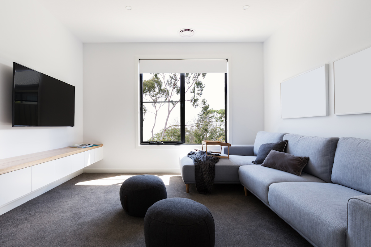 Des toiles opaques couvrent une fenêtre dans un salon moderne minimaliste et axé sur la télévision.
