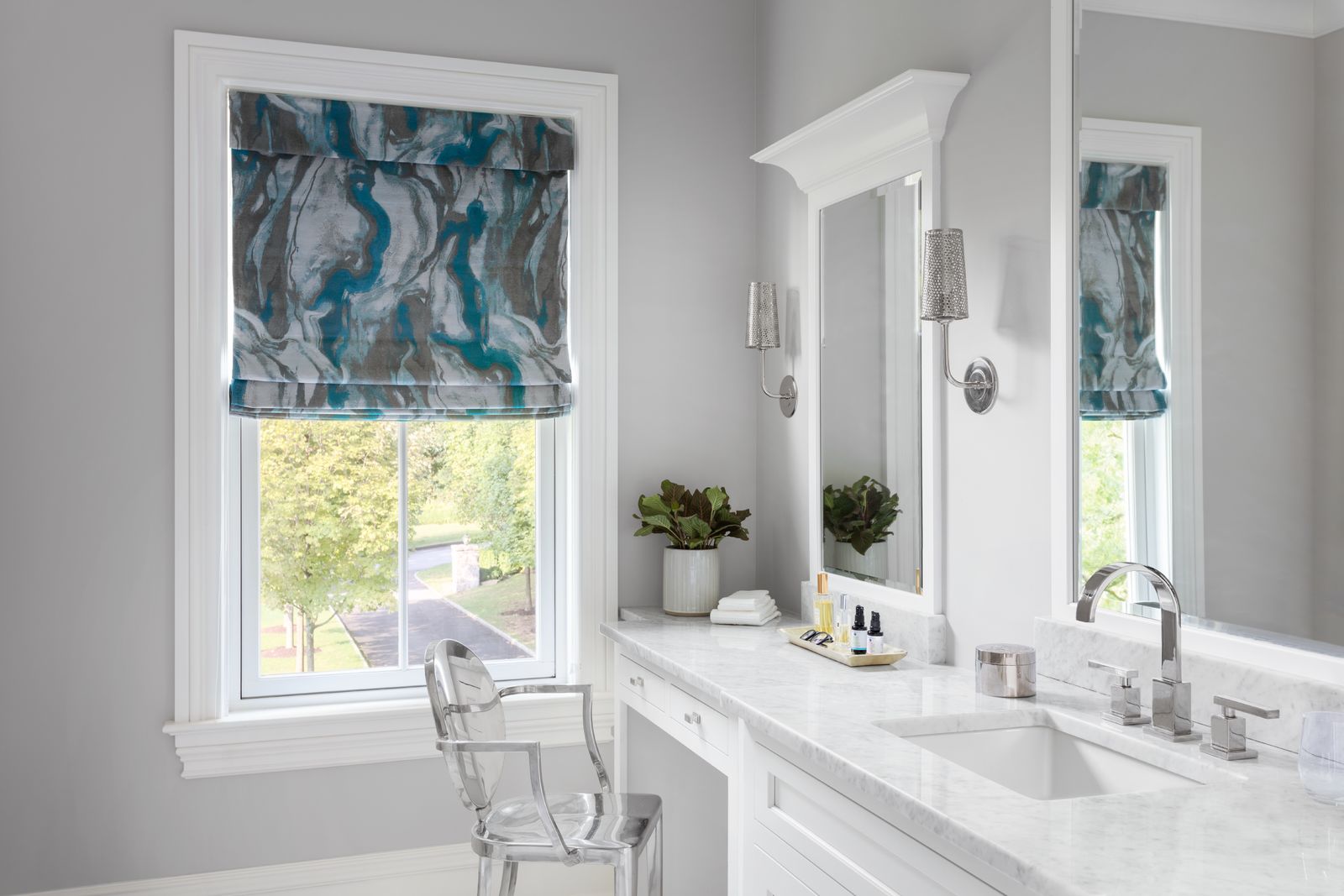 A small, modern bathroom features a Roman shade with a decorative marbled print.