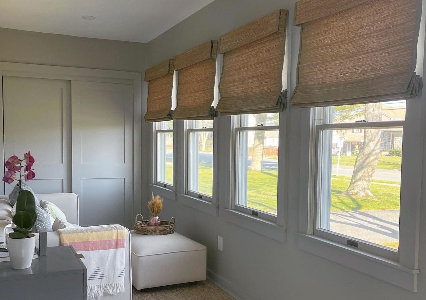 Woven wood shades cover windows in a modern sunroom