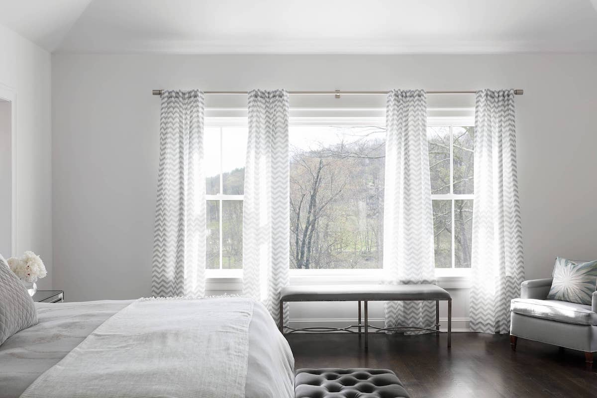 Light grey and white chevron print sheer drapes in a spacious bedroom