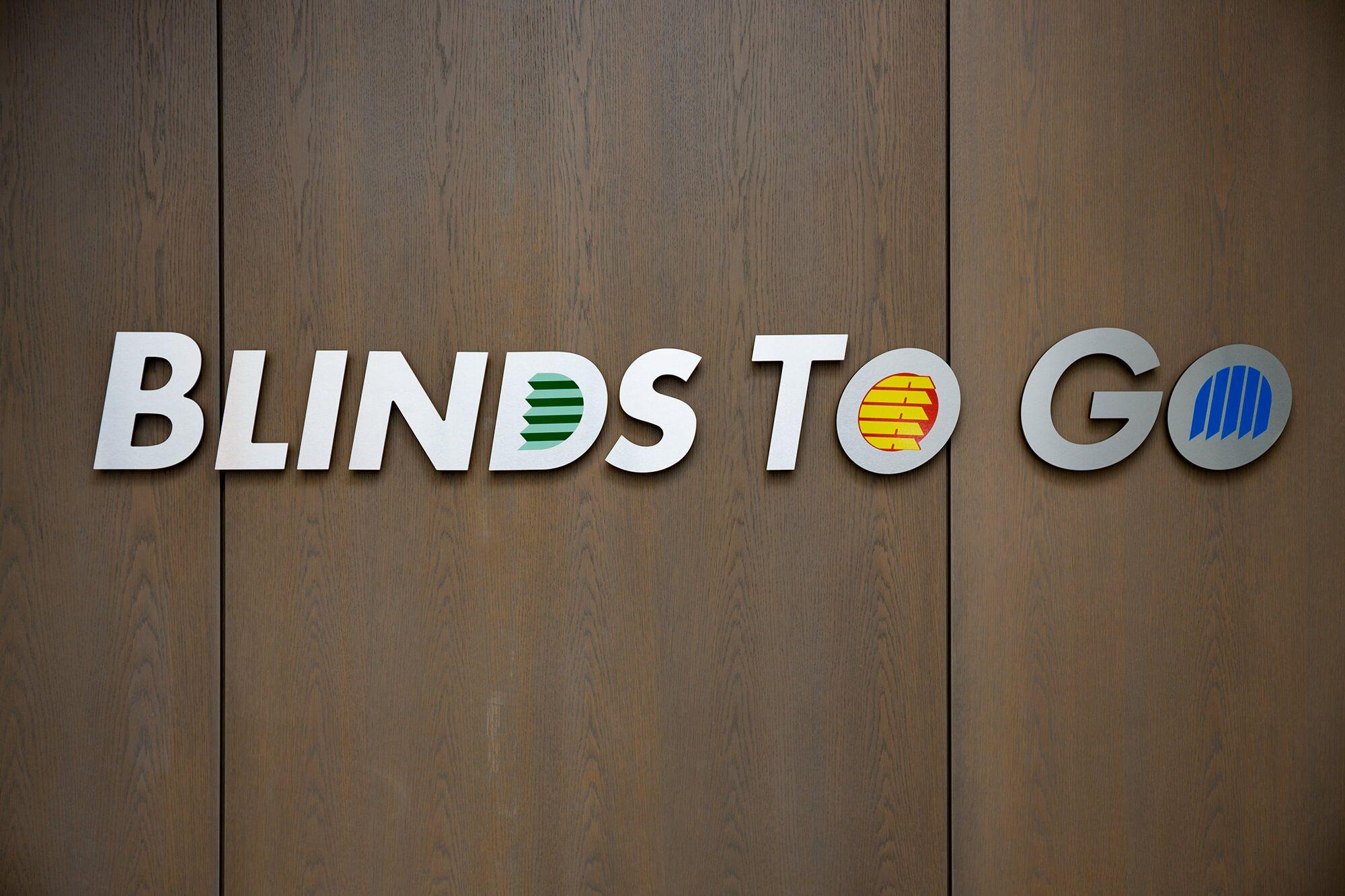 Blinds To Go logo on wood background.