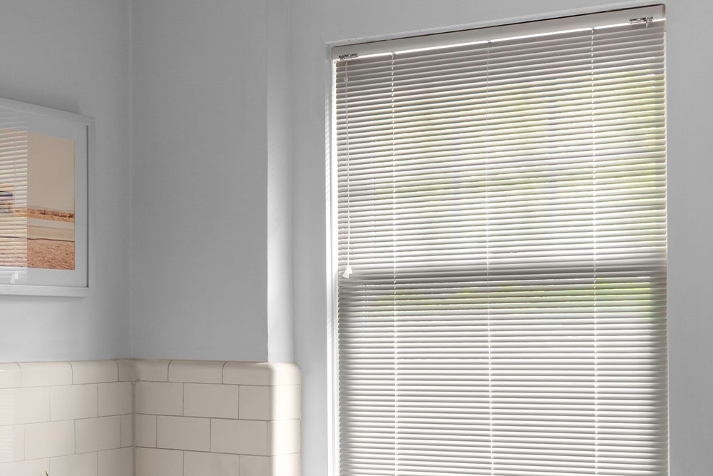Micro-mini aluminum blinds cover a large window in a modern bathroom.
