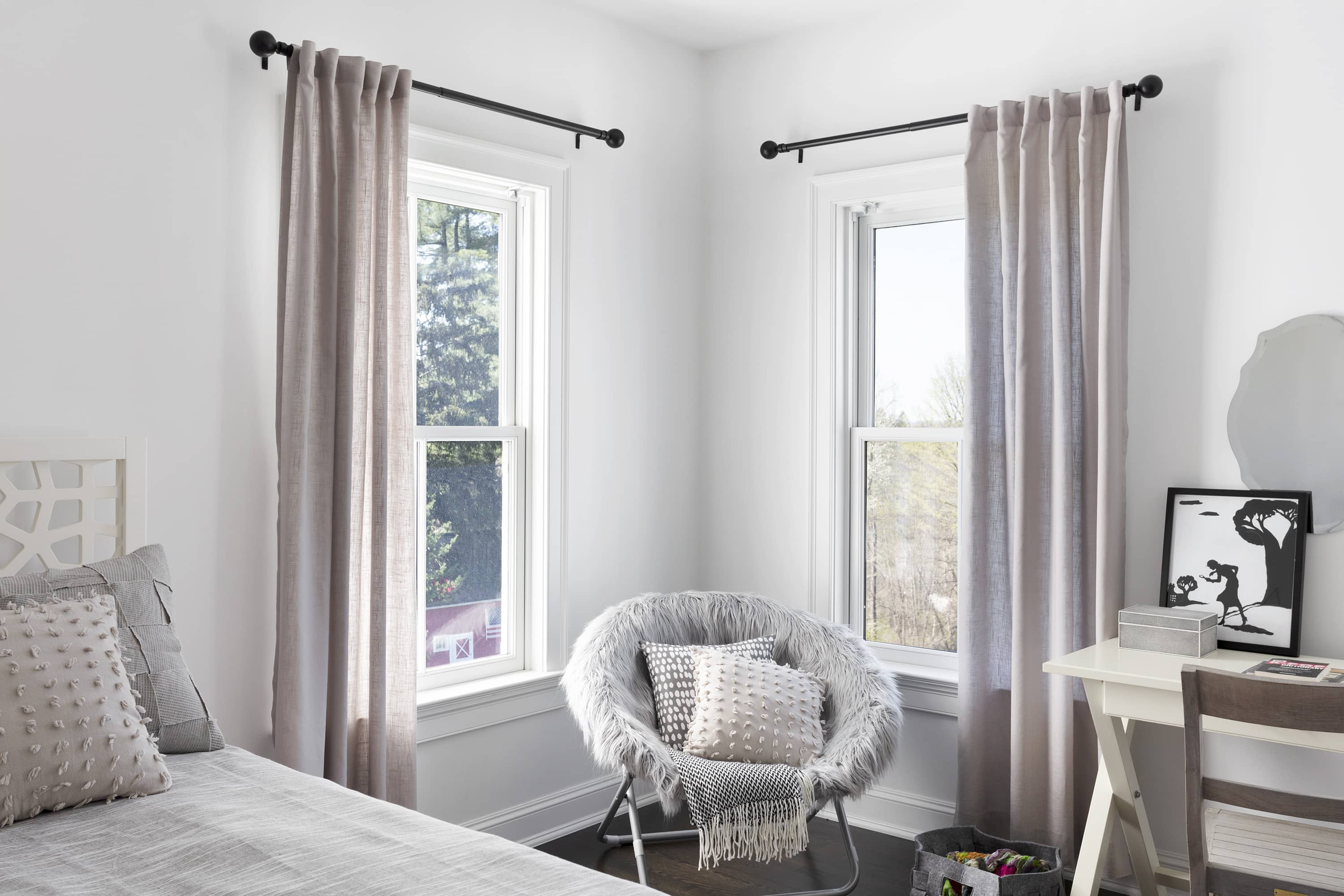 A bedroom features two windows with drapes with a classic outside mount.</p alt=