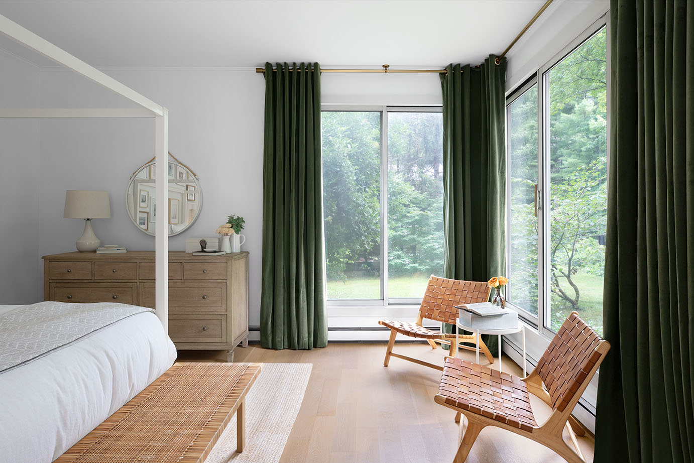 Des rideaux de velours vert forêt recouvrent deux grandes fenêtres dans une chambre moderne.