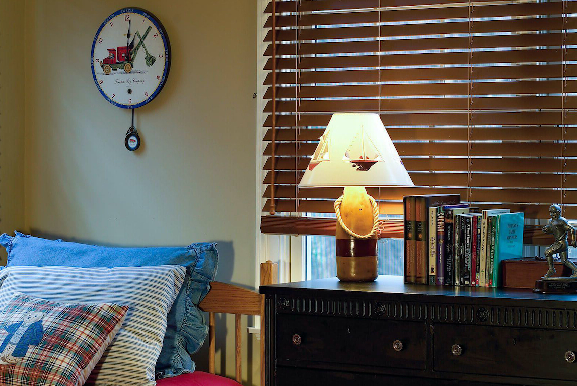 A kids bedroom decorated with modes of transportation features cordless faux wood blinds on the windows