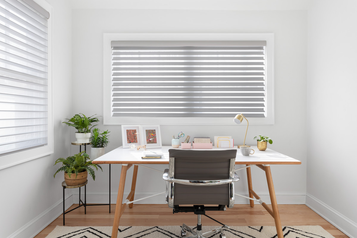 Grey Serenity sheer shades with a motorized wand cover two large windows in a small home office.