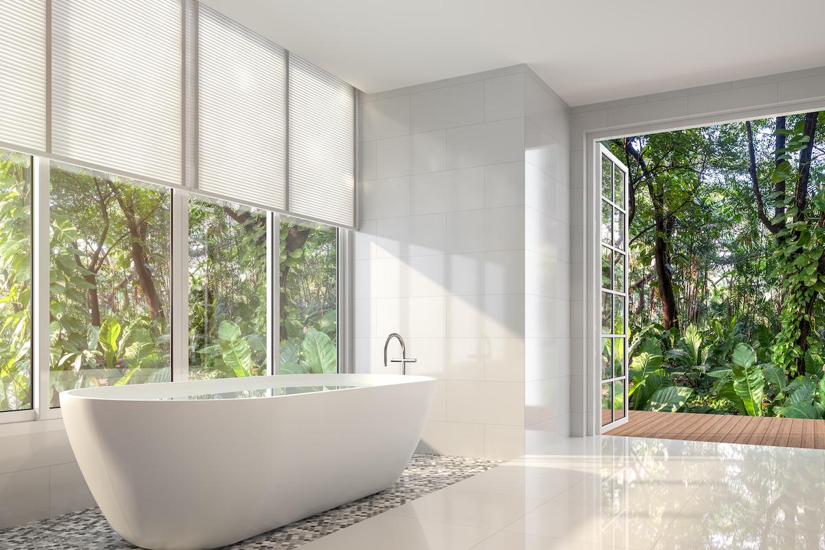 A wall of hard to reach windows behind a large contemporary bathtub show the perfect place for motorized shades.