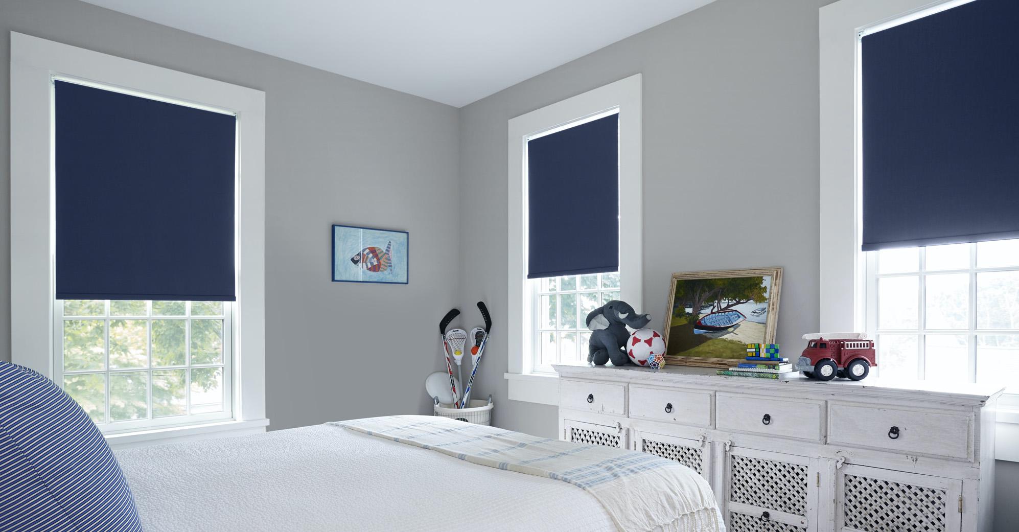 A playful kids room features blue cordless roller shades on three windows.