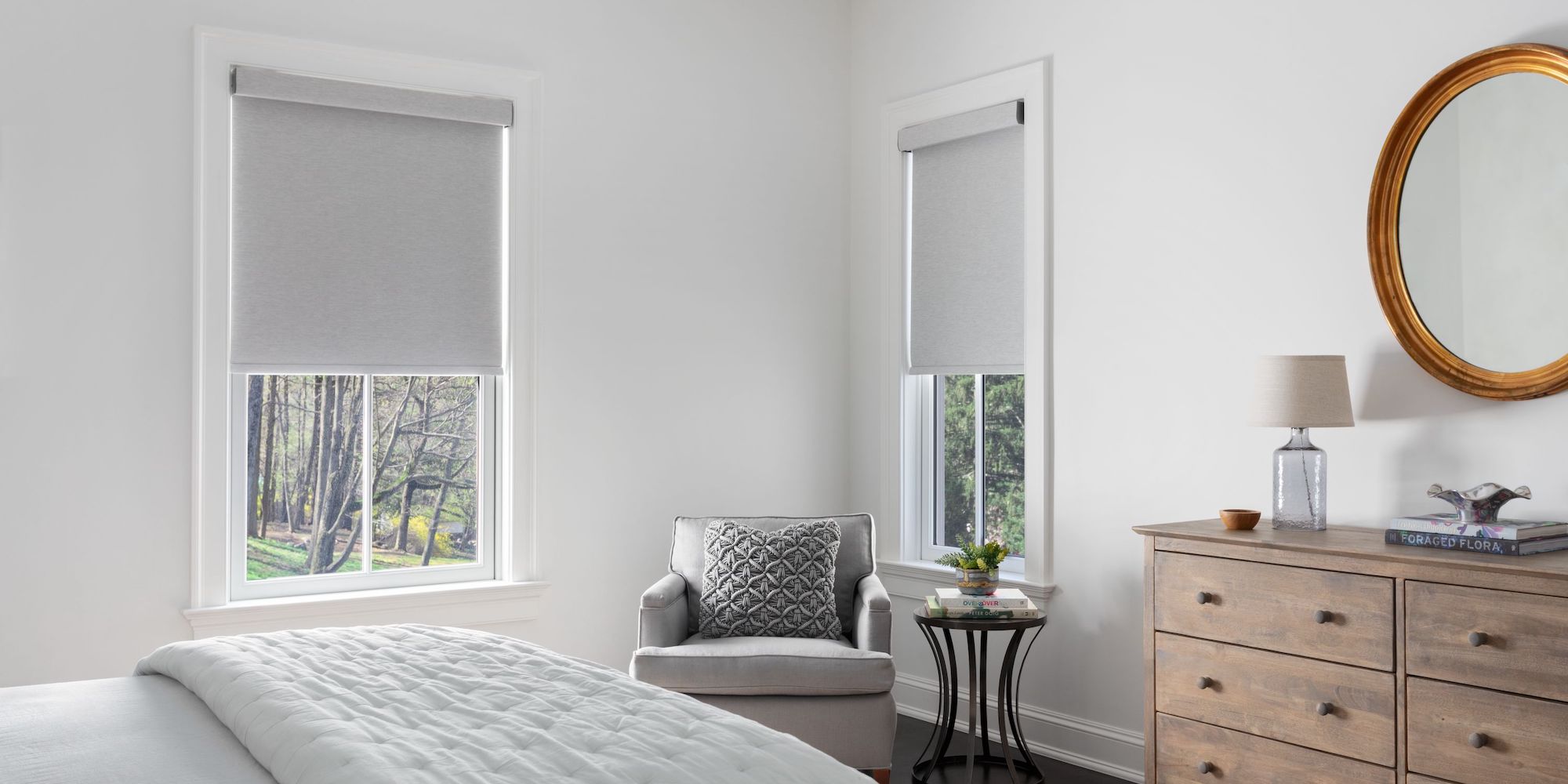 Light grey roller shades allow light to pour into in a modern bedroom.