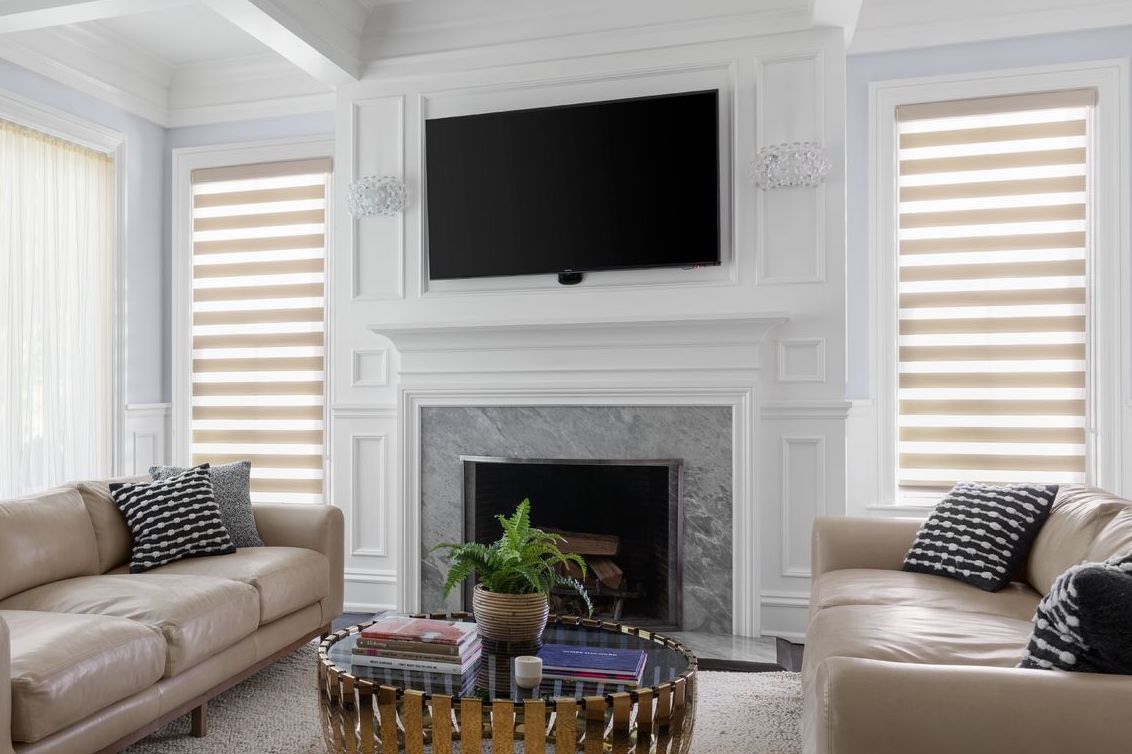 Cascade sheer shades in a caramel color cover two tall windows in a living room.