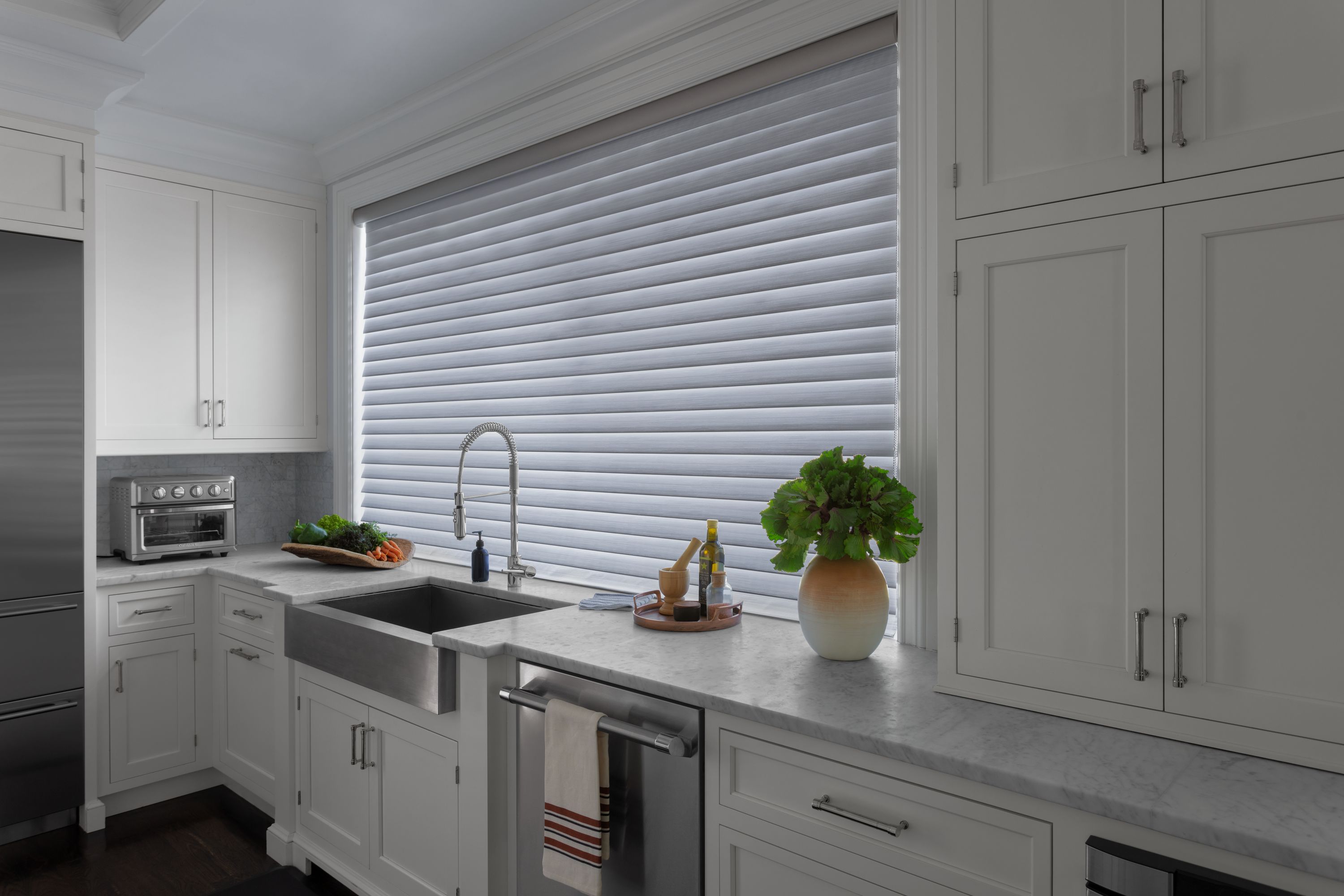 Room-darkening Serenity sheer shades in grey cover a large window over a kitchen sink.