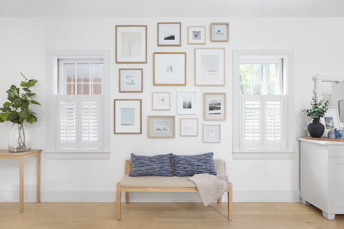Ideal shutters in the café style cover the bottom half of two windows in a bright, modern living room.