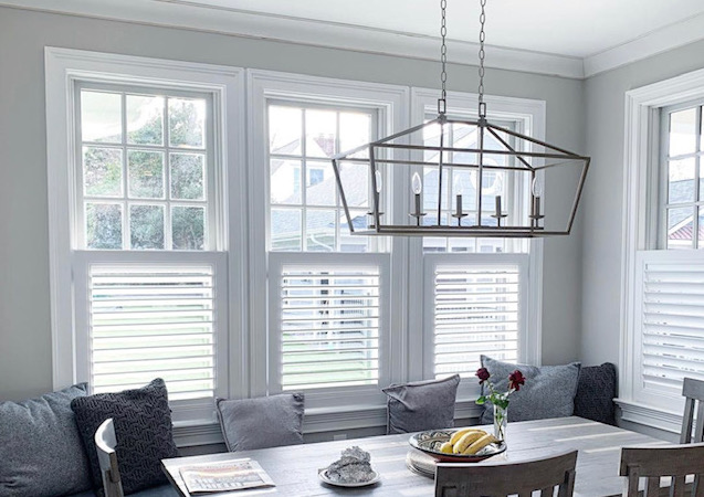 The dining area of an eat-in-kitchen features cafe-style shutters on the bottom half of the windows.