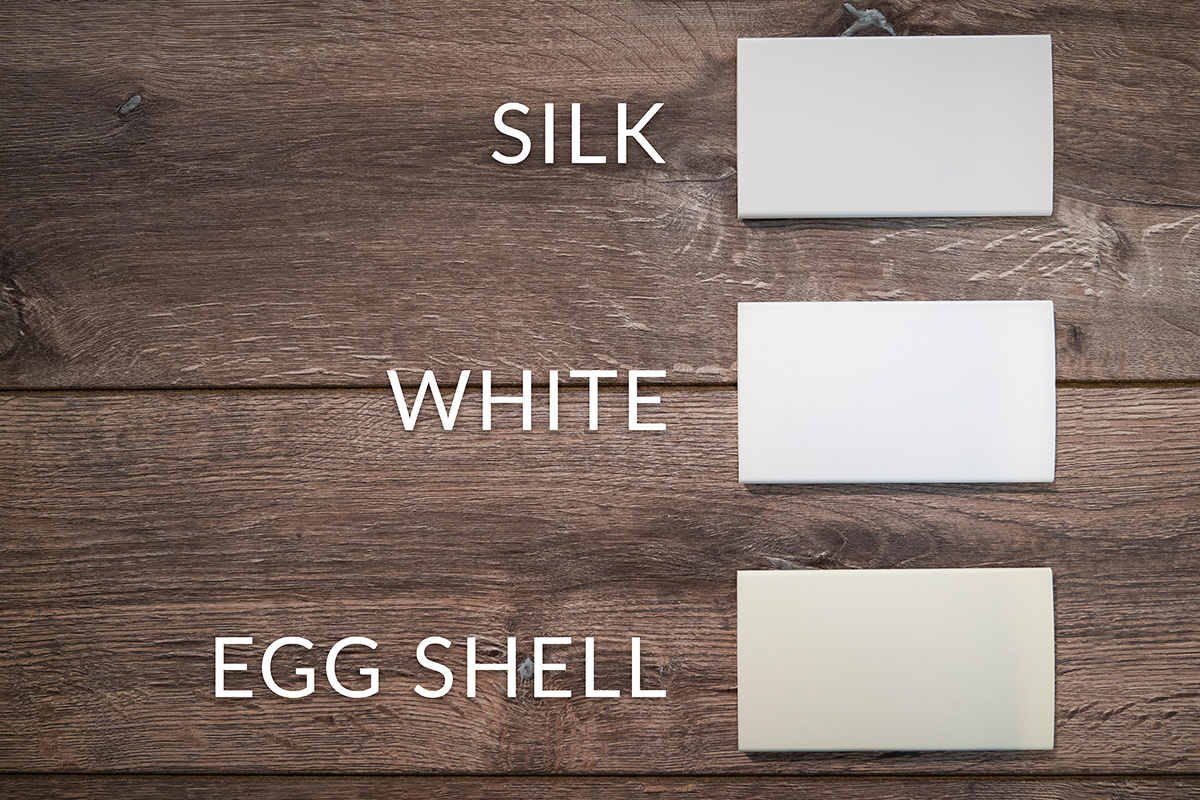 Three different white swatches of shutters laid on a table and labeled