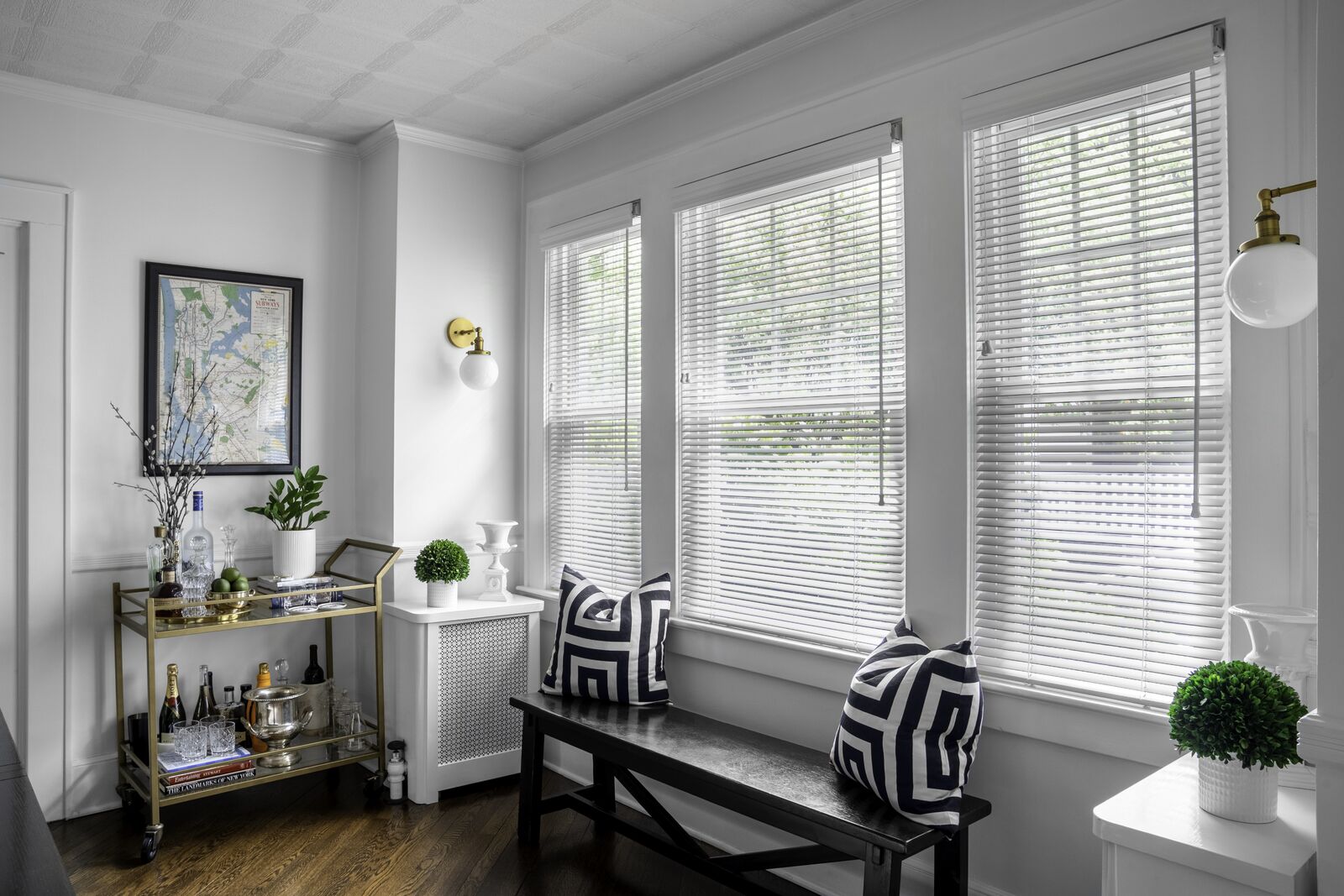 A modern front room with large windows is decorated with wooden blinds.