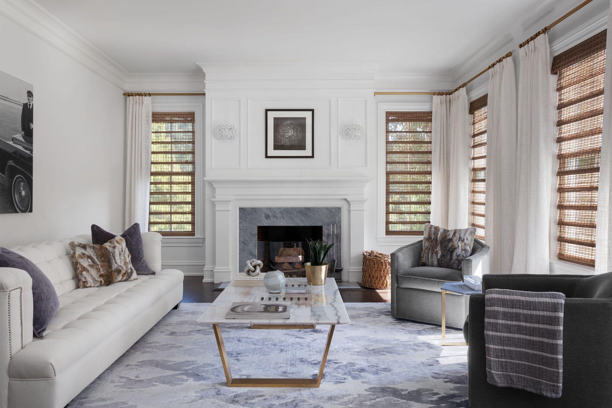 A contemporary living room features white linen drapery and unlined woven wood shades in a beautiful natural wood tone