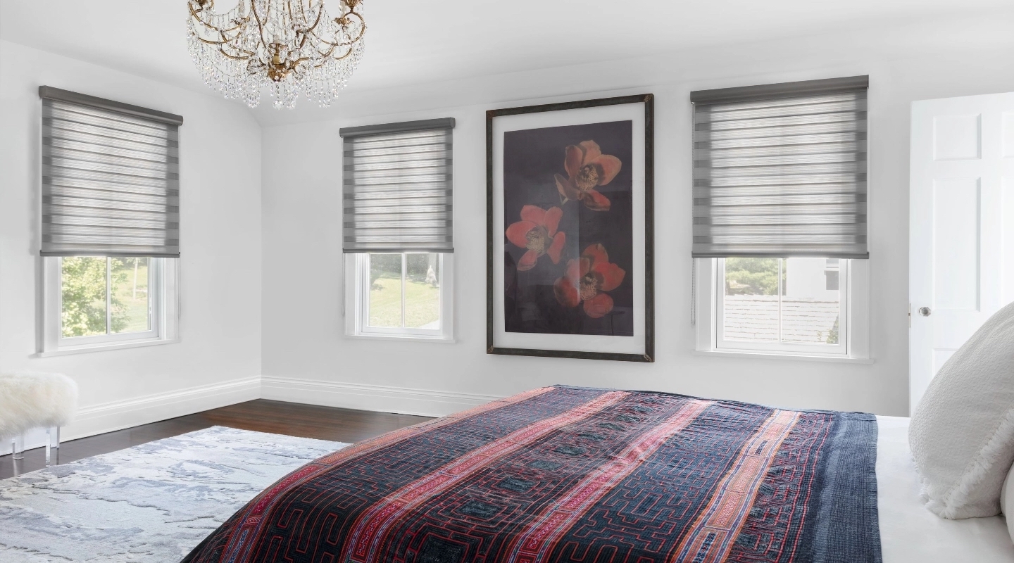 Grey sheer vertical blinds are partially closed in large contemporary bedroom.