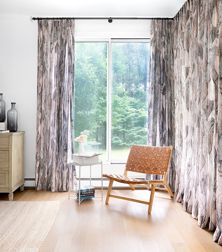 Sheer floor-to-ceiling drapes with a feather pattern covers two adjoining sliding glass doors in a modern home.