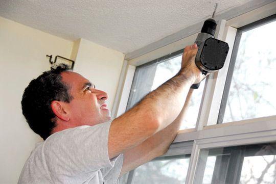 man installing window treatment