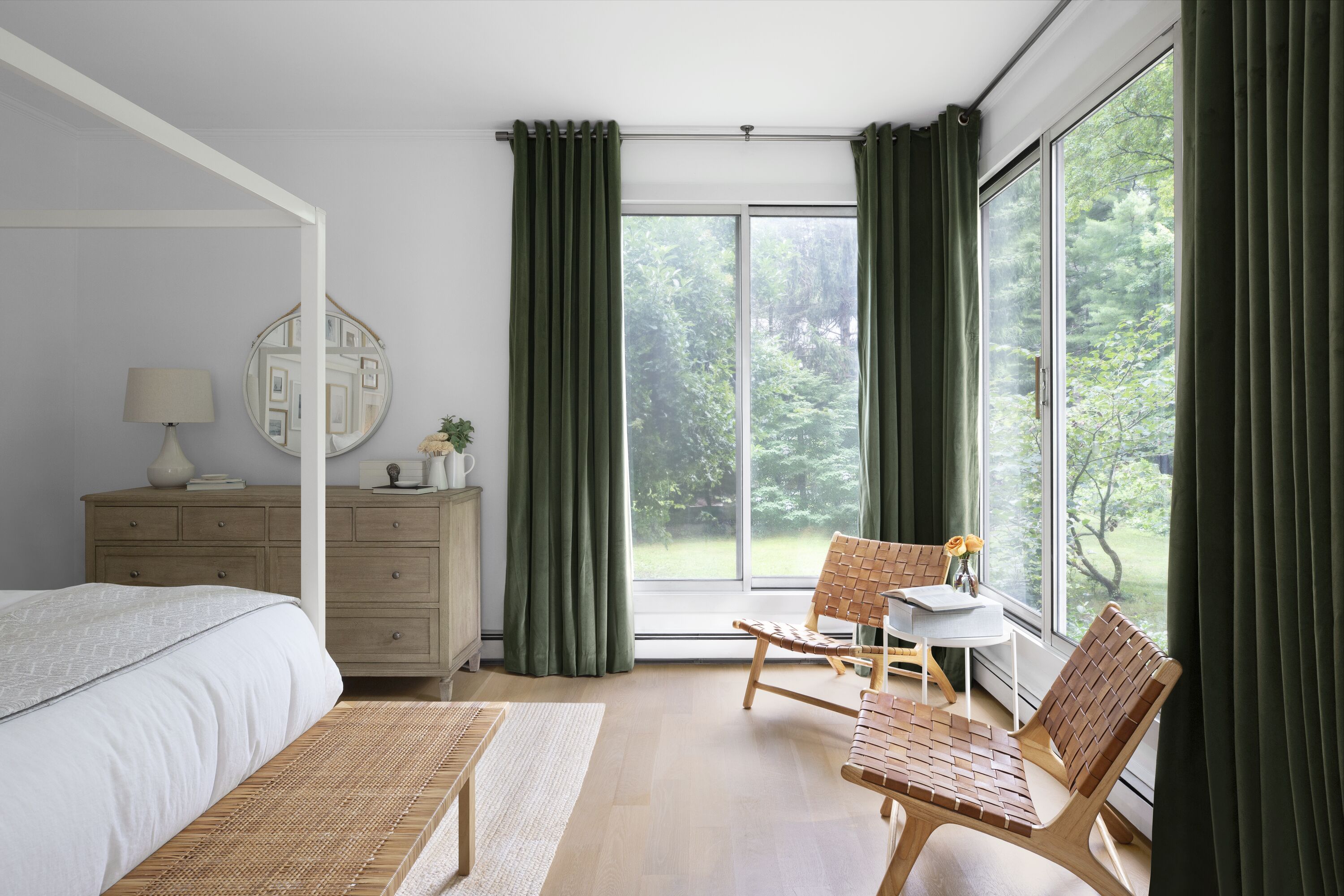 Ceiling mounted drapery in a rich olive green hue perfectly frames the view of a bedroom with natural-inspired furniture