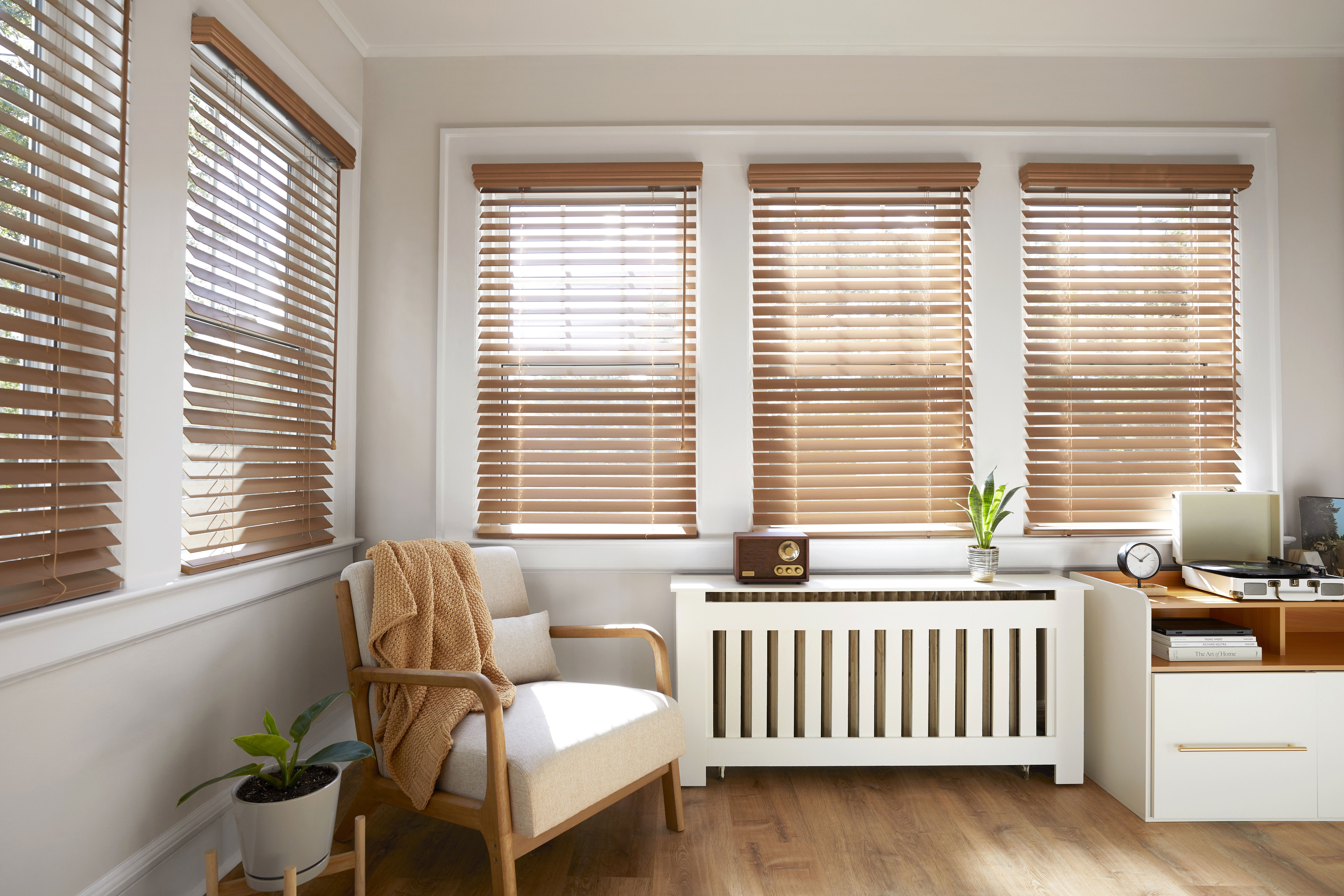 Real wood blinds tilted open in a bright sunroom.