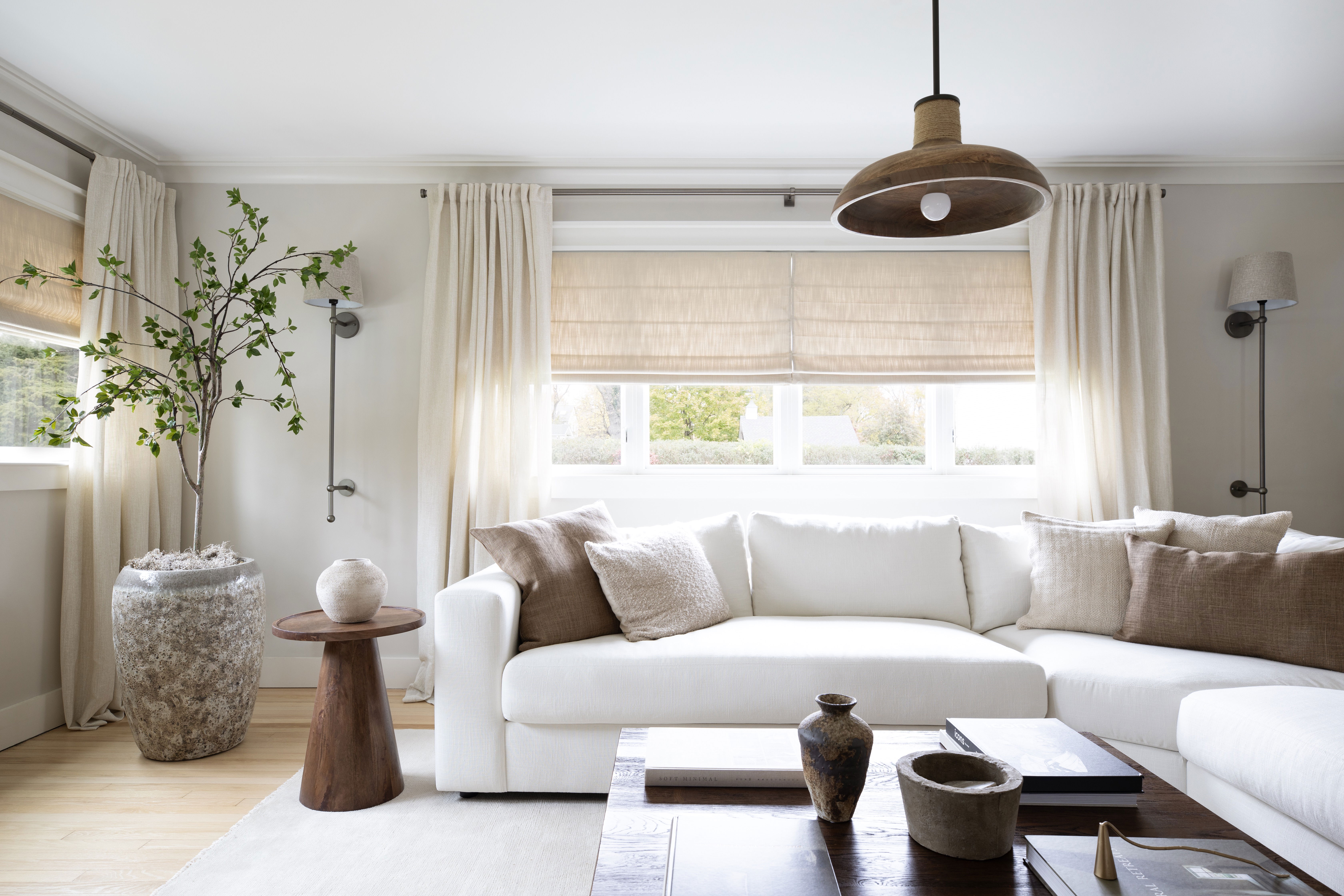 Warm living room with brown accents and Roman shades paired with light-filtering drapery.
