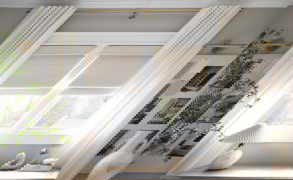 Neutral light-filtering curtains frame cream-colored roman shades on two windows in a contemporary study