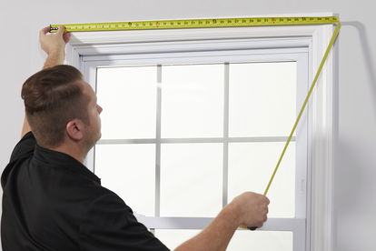 A measure technician measures a window frame. A measure technician measures a window frame.