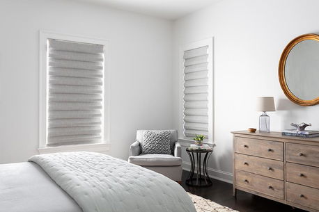 Classic fold roman shades in light grey cover two windows in a modern bedroom