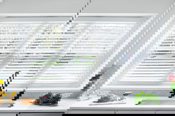 Faux wood blinds for windows in bright white and wood tones, combining style and durability for effective light control and privacy.