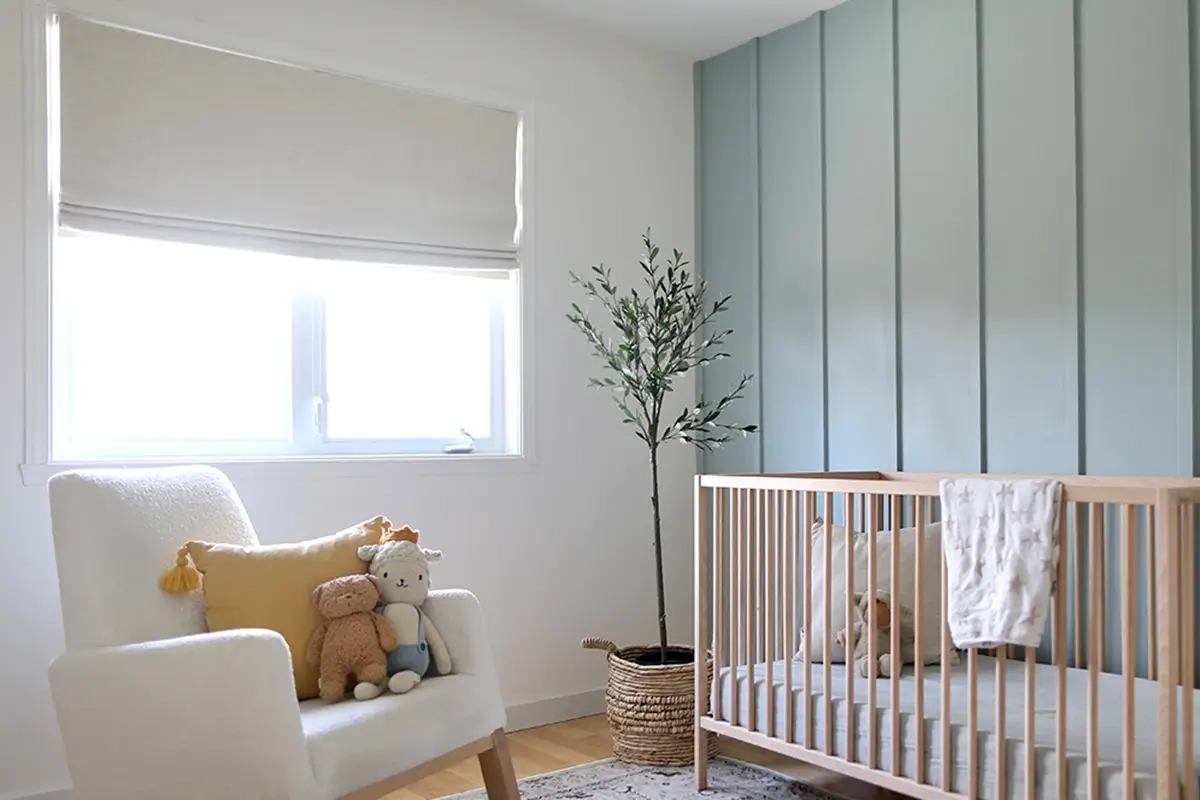 A tan-colored linen flat roman shade covers a large window in a modern nursery A tan-colored linen flat roman shade covers a large window in a modern nursery